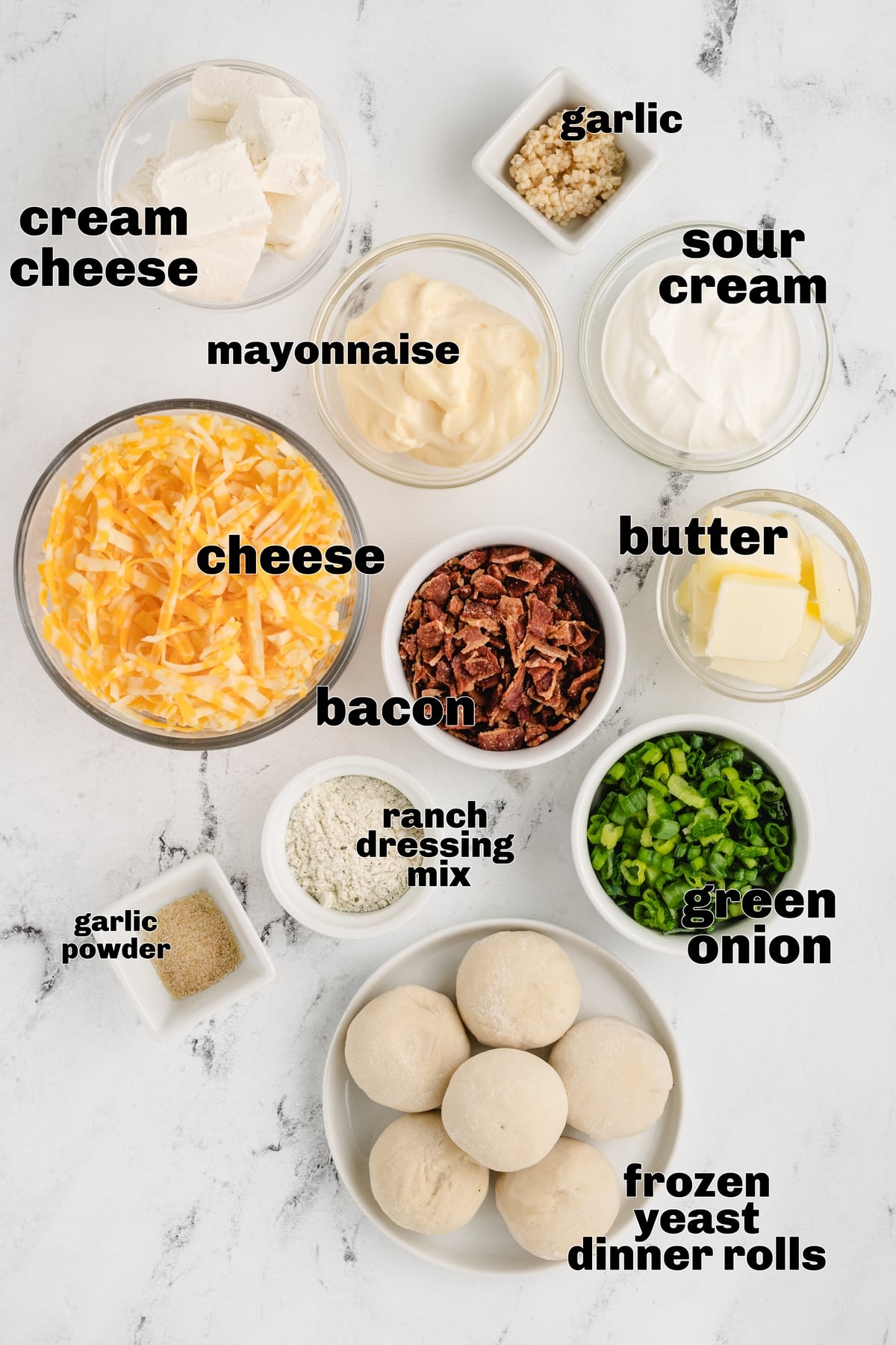 Ingredients for sour cream bacon ranch ring dip: cream cheese, sour cream, mayonnaise, shredded Colby Jack cheese, cooked bacon, green onions, garlic, ranch seasoning, and frozen dinner rolls.