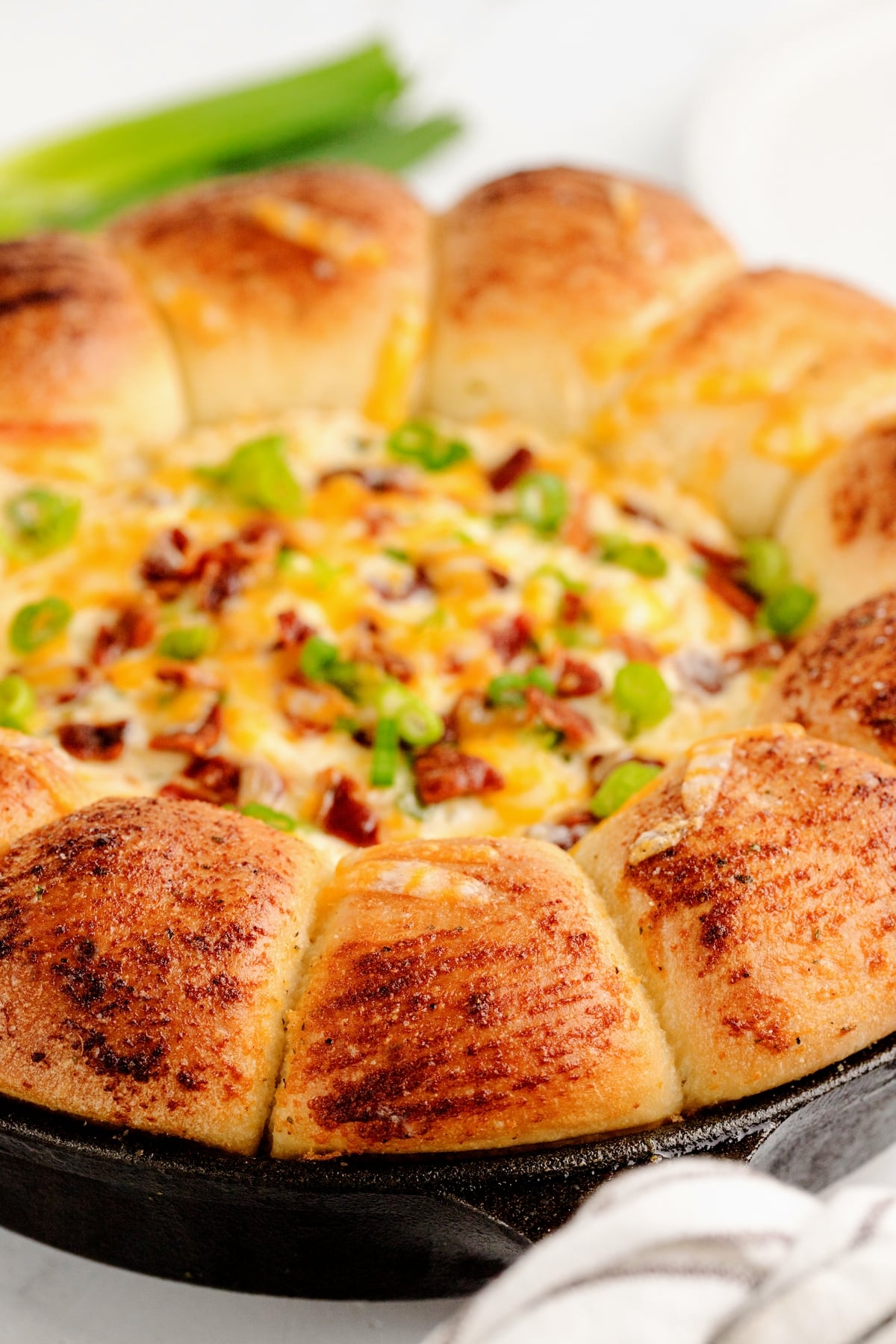 Close-up of a golden-brown sour cream bacon ranch ring dip in a cast iron skillet.