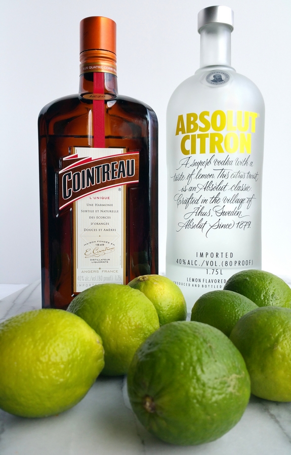 Bottle of Cointreau and Absolut Citron vodka with limes.