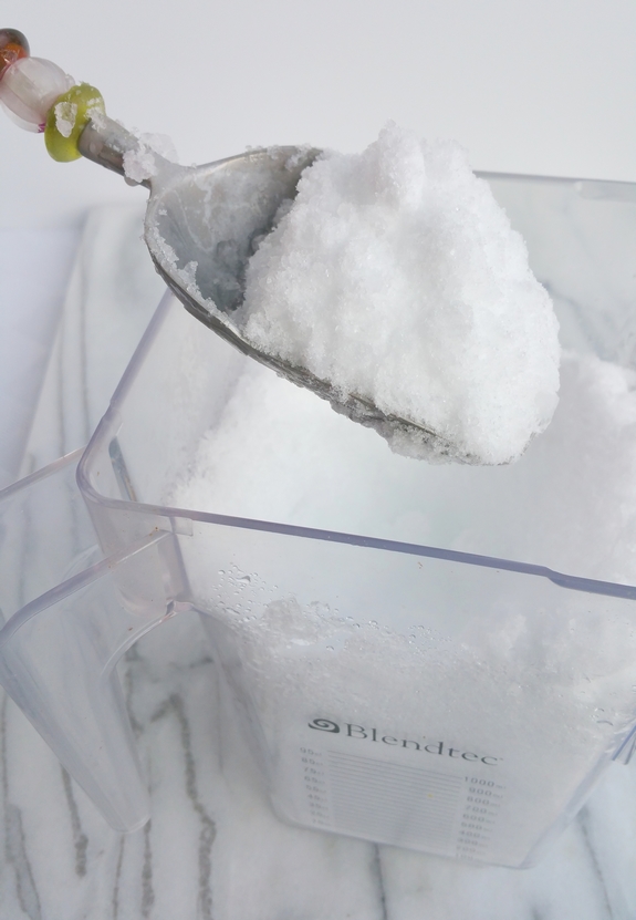 Crushed ice in a blender being scooped out.
