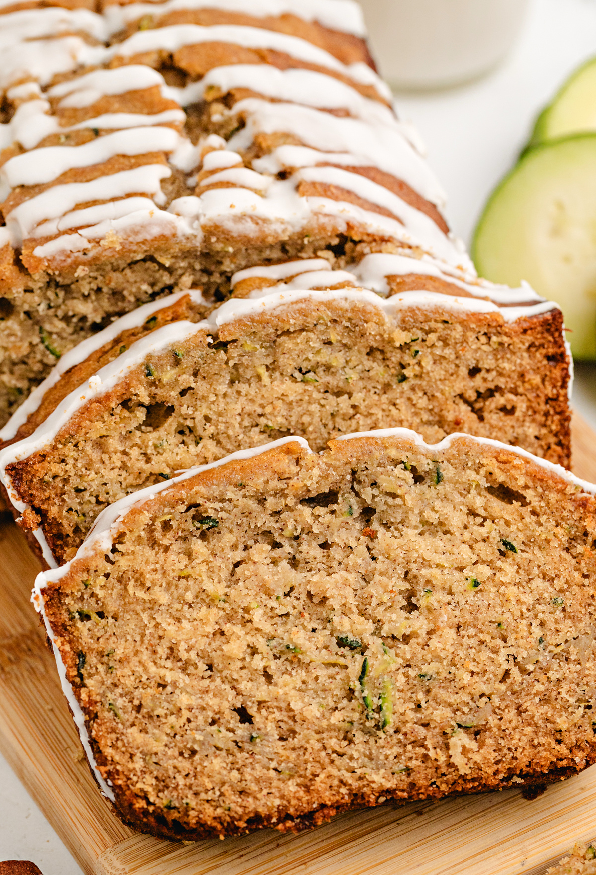 Sliced honey zucchini bread on a cutting board with glaze and visible zucchini flecks