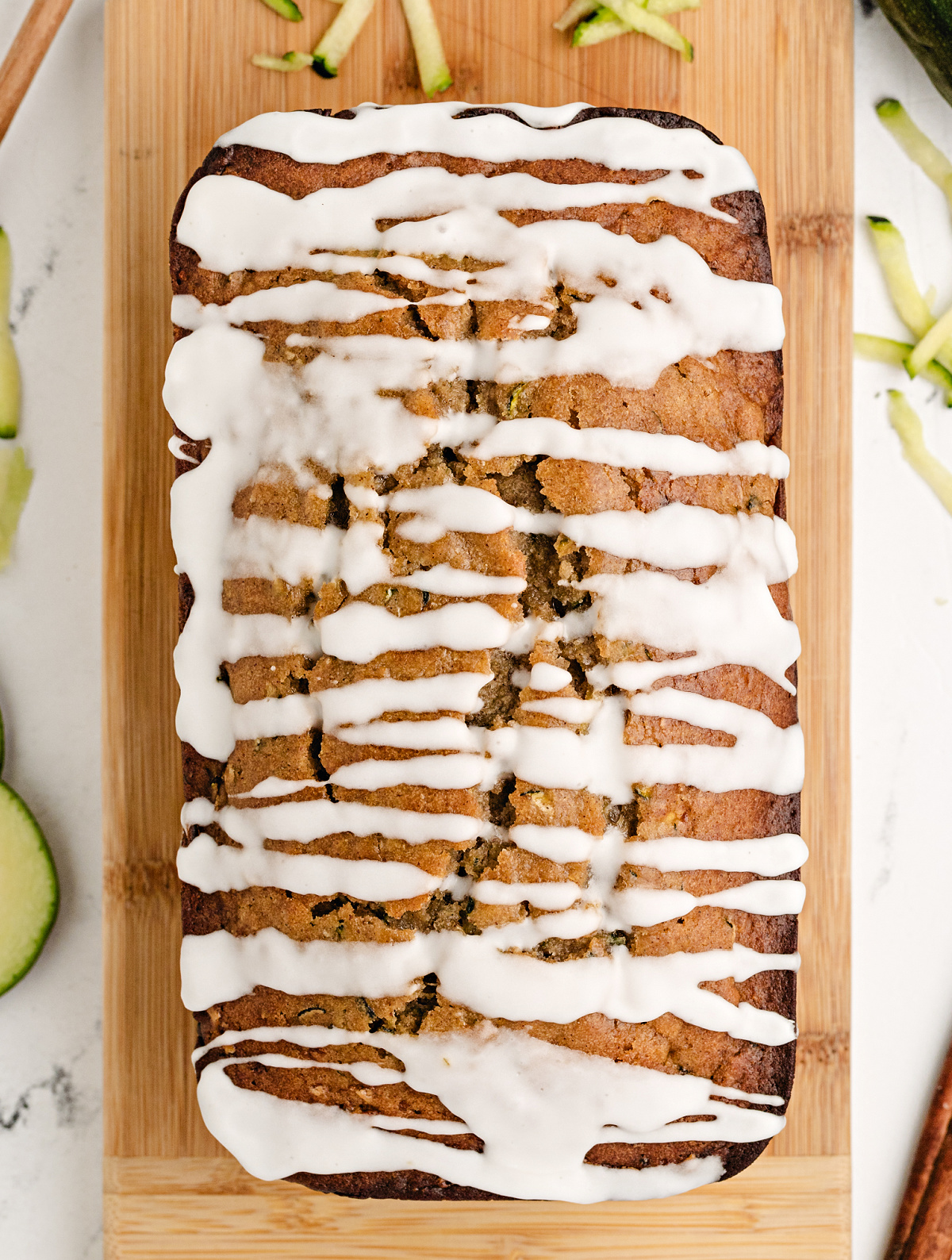 Overhead view of zucchini bread with honey and glaze, cooling on a wooden board