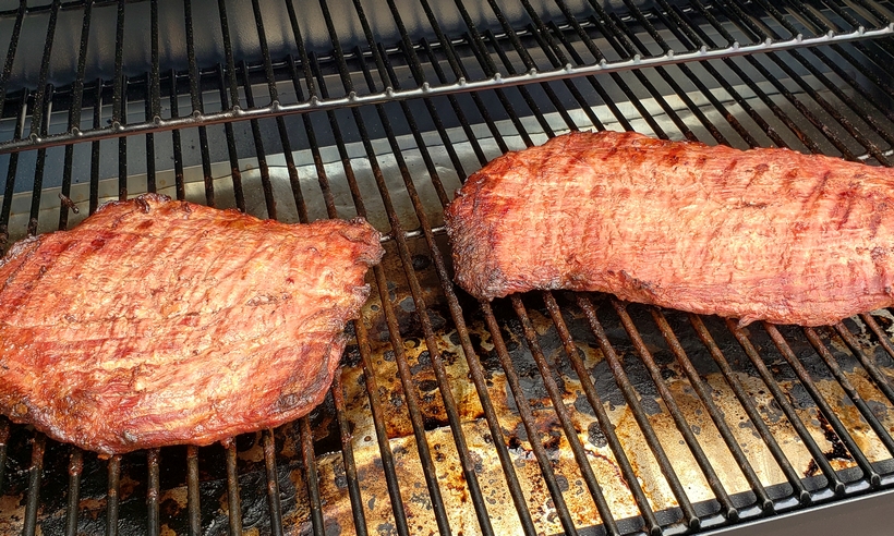 Make the best street food at home with these Flank Steak Tacos with Garlicky Cilantro Chimichurri. These tacos are essentially going to be your go-to summer, grilling meal. #noblepig #grilling #beef #flanksteak #chimichurri Two flank steaks sitting on a grill plate.