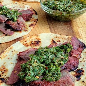 Flank steaks tacos, three of them, with bowl of chimichurri.