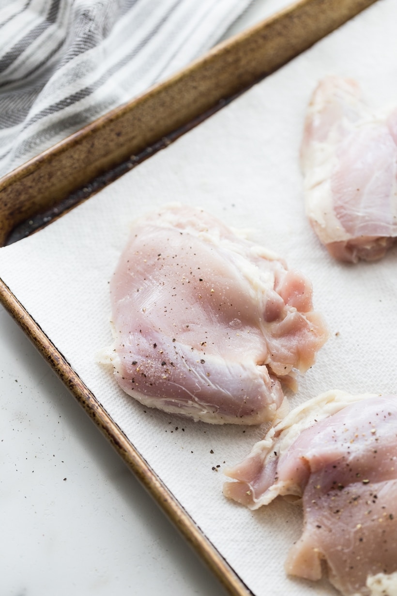 raw Air Fryer Caribbean Spiced Chicken Raw chicken thighs laid out on a baking sheet, prepped for seasoning.