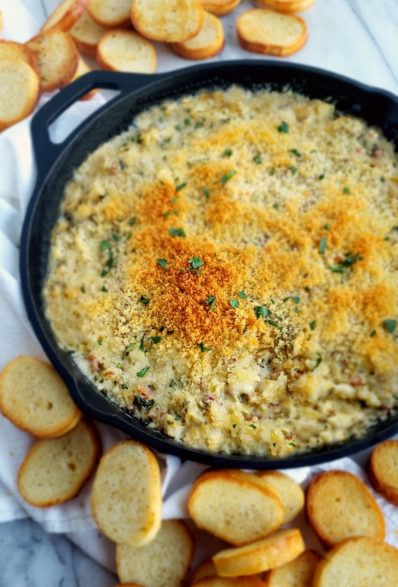 Brie, crab and artichoke dip in a cast iron skillet.