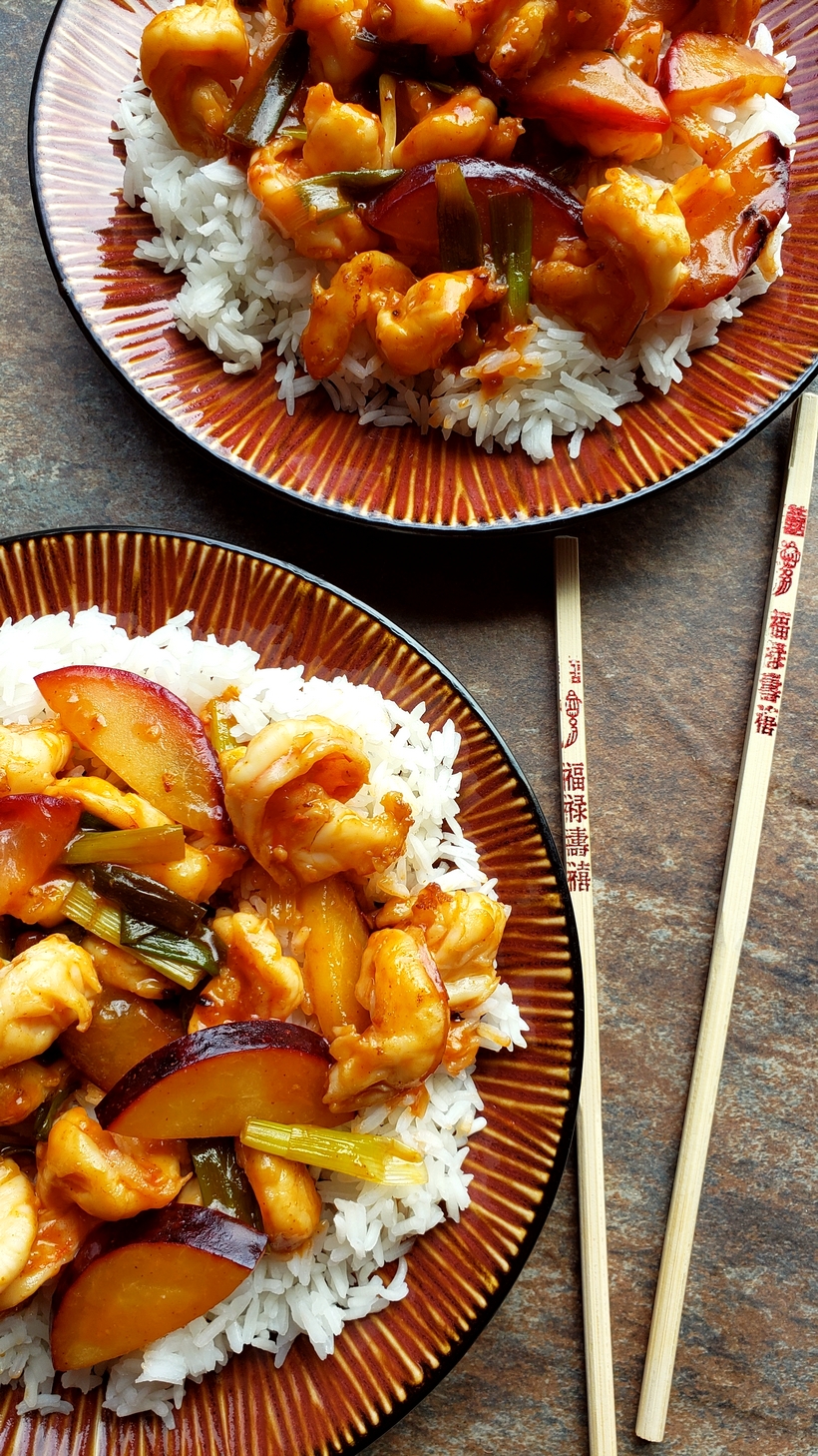 This Easy Shrimp and Fresh Plum Stir-Fry will have you in and out of the kitchen and eating fast. Easy Shrimp and Fresh Plum Stir-Fry over rice with chopsticks on two different plates.