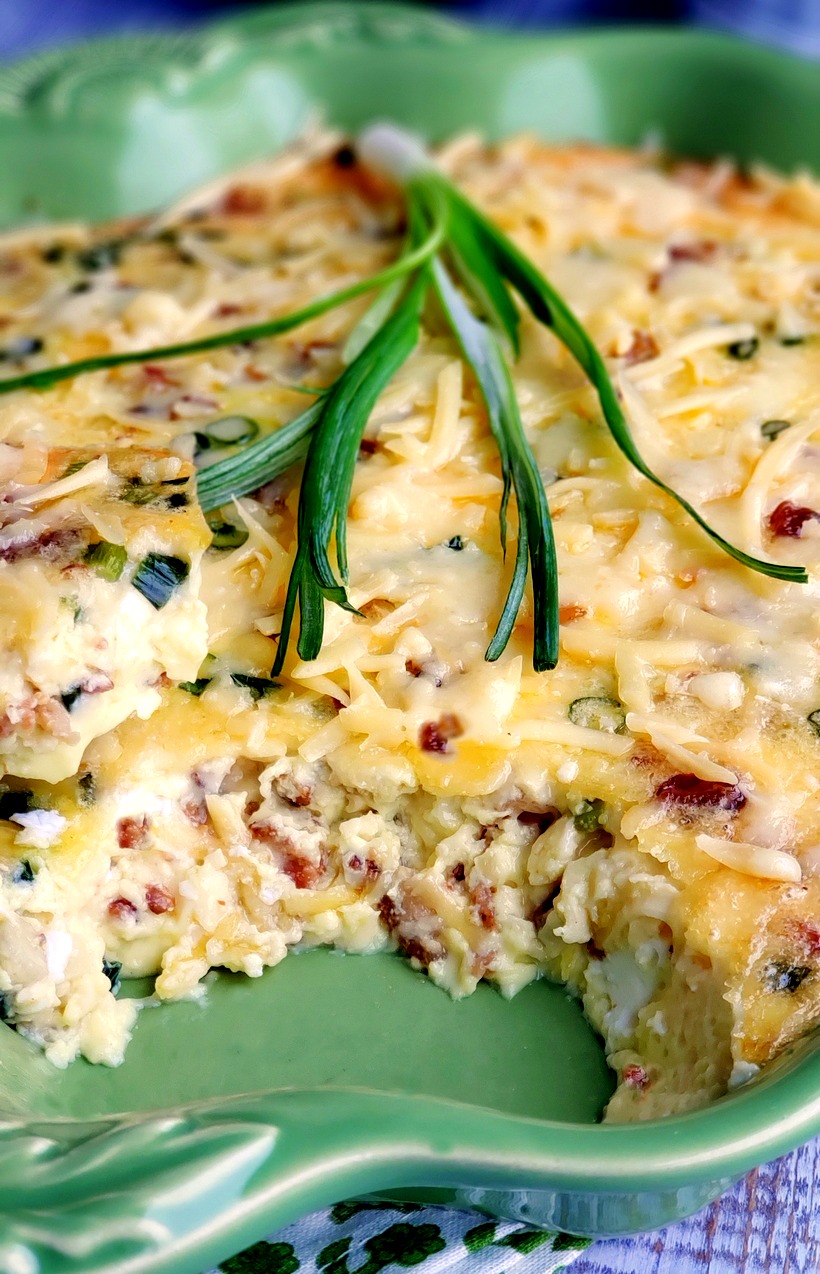 A decadent and sumptuous brunch recipe, this Mouthwatering Oven Omelet will have you wondering why you make eggs any other way. Everyone at your breakfast table will imagine you fussed over this easy omelet, when in reality this egg dish takes very little time to put together. #noblepig #ovenomeletterecipe #ovenomelet #breakfastcasserole #brunchrecipe #bakedomelette #bakedomelet #bruncheggs #bruncheggsforacrowd #bruncheggideas #breakfastfordinner #bruncheggscasserole #brunchideas Omelet with a serving removed in a green dish.