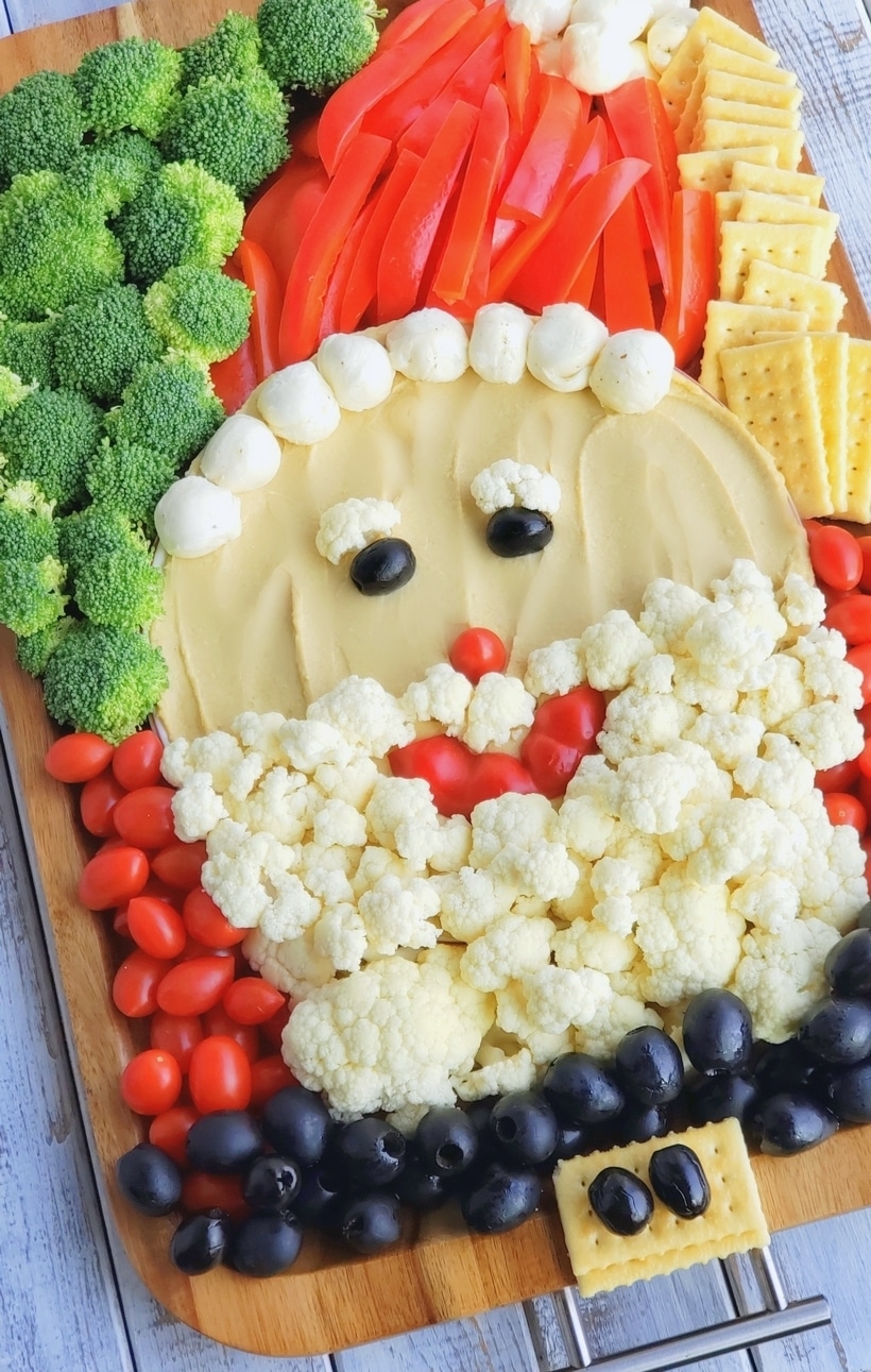 This Santa Snack Board is the perfect holiday centerpiece for every gathering this season. Not only is this healthy snack board festive and fun, it uses simple ingredients everyone loves. This Santa Board transports easily, feel free to take it along to every celebration this season. #noblepig #santasnackboard #diysantasnackboard #diy #healthysnackboard #christmas #christmasrecipes #easychristmasrecipes #holidayrecipes #santafood #santa #holidayentertaining #holidayfood #christmasappetizer Santa face made with vegetables.