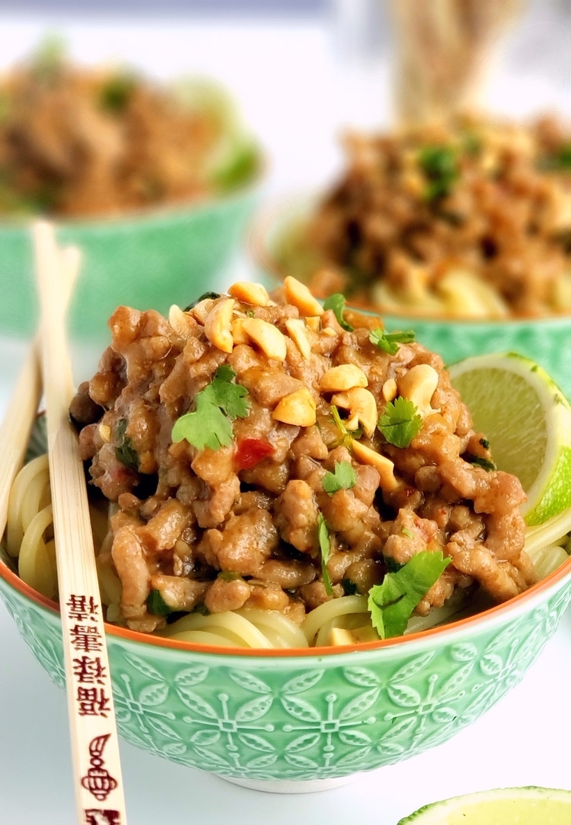 Dan dan pok noodles in three bowls with chopsticks.