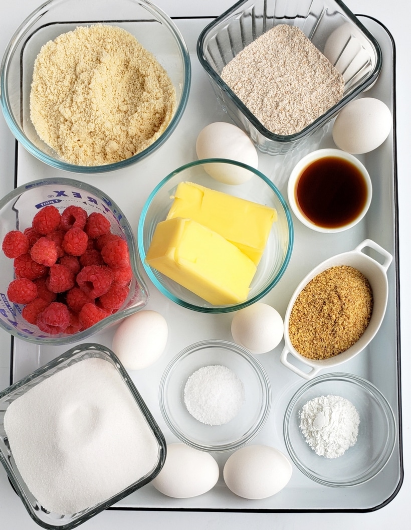 A tray of ingredients for healthier raspberry cake all in different bowls.