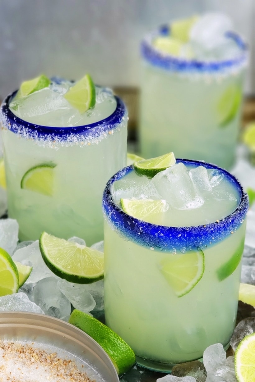 Three ingredients is all you need to make this outstanding margarita with agave as its sweetener. Perfectly balanced and refreshing, this agave margarita recipe will be your new favorite patio drink. Three agave margaitas in glasses surrounded by ice and lime.