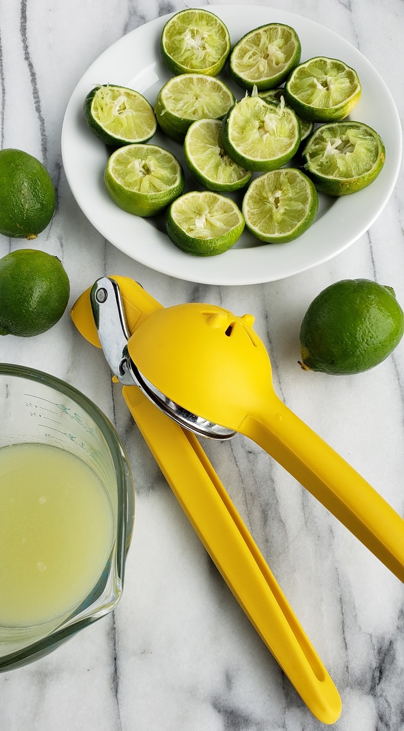 Three ingredients is all you need to make this outstanding margarita with agave as its sweetener. Perfectly balanced and refreshing, this agave margarita recipe will be your new favorite patio drink. Lime juice, squeezed lime and citrus squeezing tool on white marble.