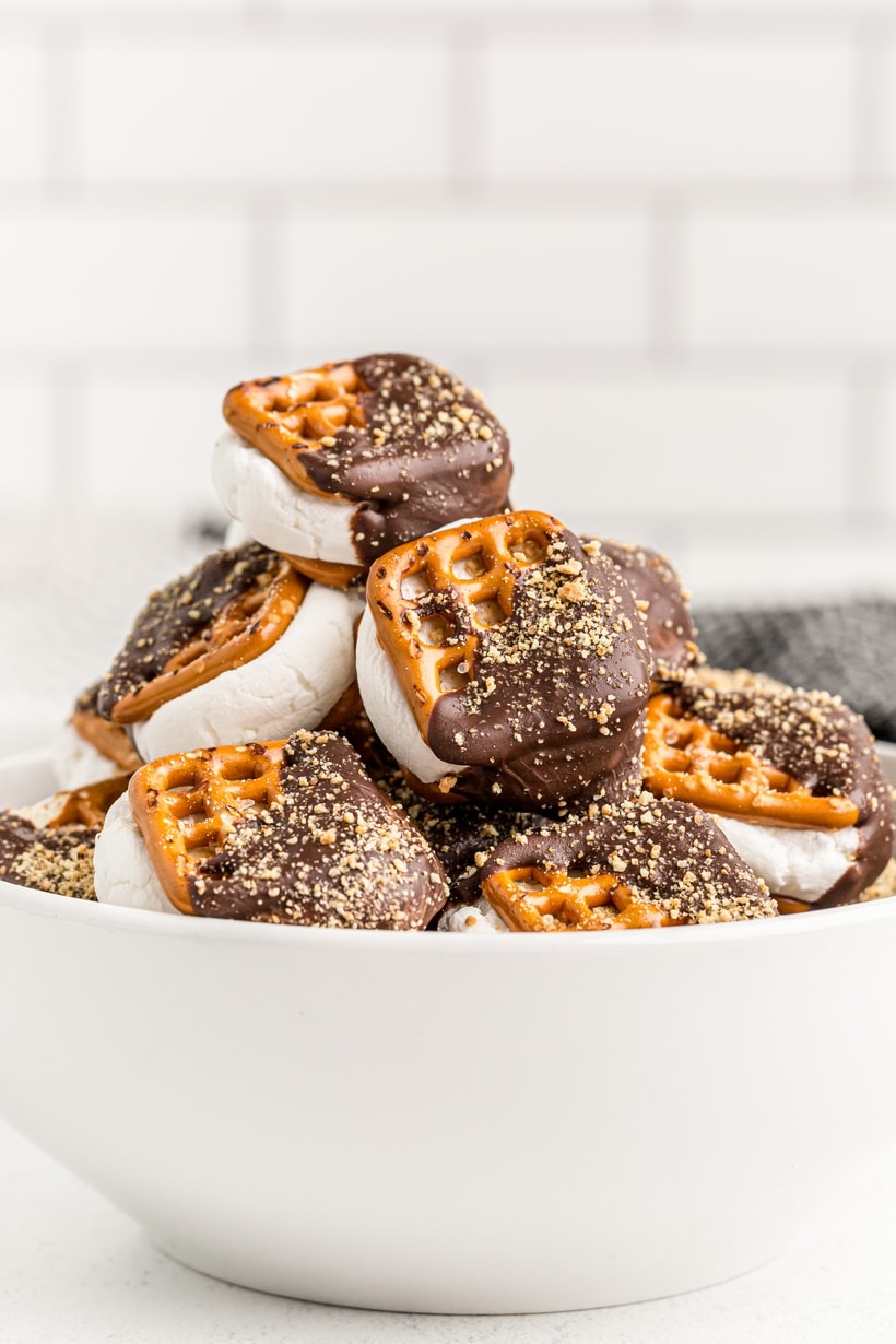 bowl of oven-baked s’mores pretzel snacks ready to serve Bowl of stacked s’mores pretzels coated in chocolate and sprinkled with crushed graham crackers