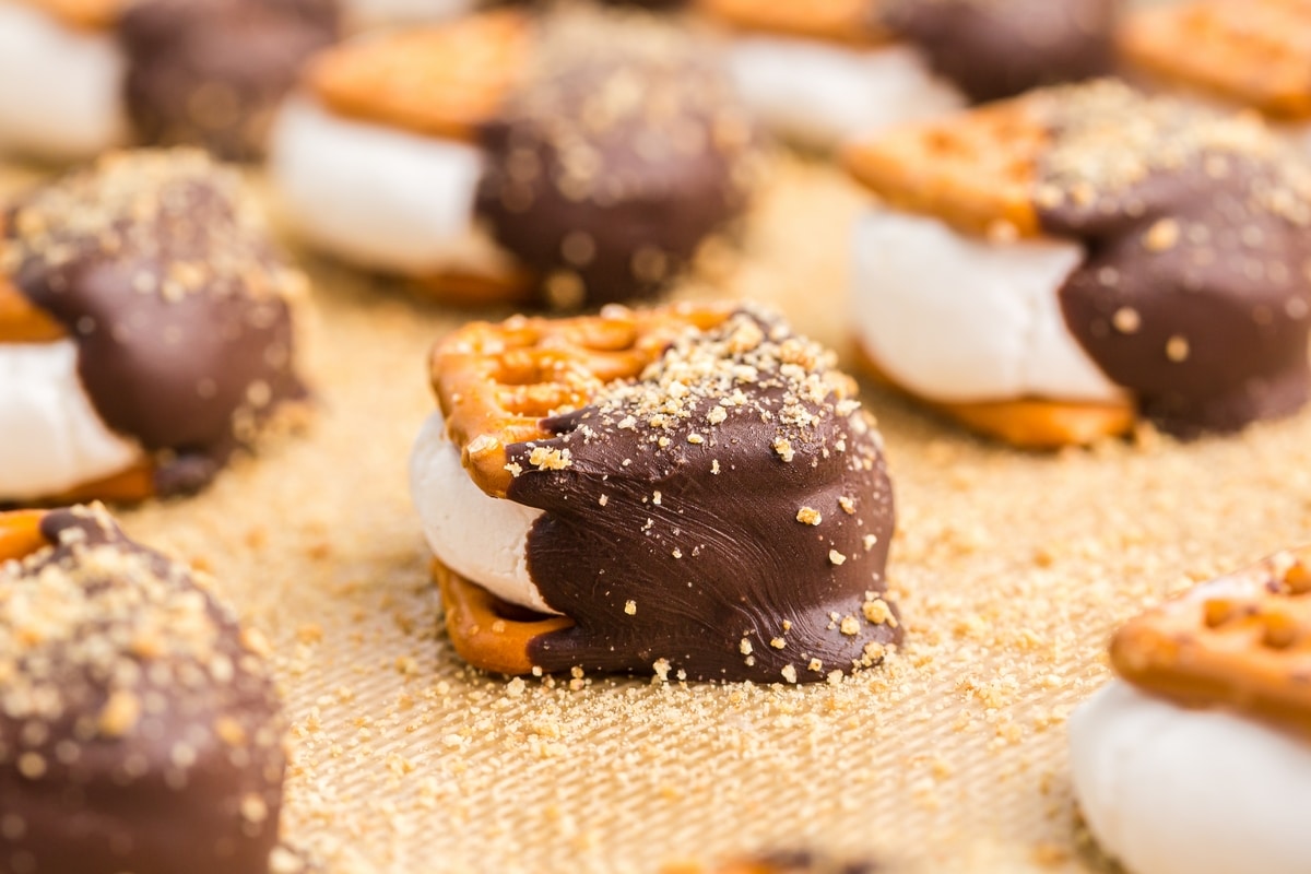 indoor s’mores pretzels cooling with chocolate and marshmallow S’mores pretzel bites on a baking mat with melty chocolate and marshmallow centers