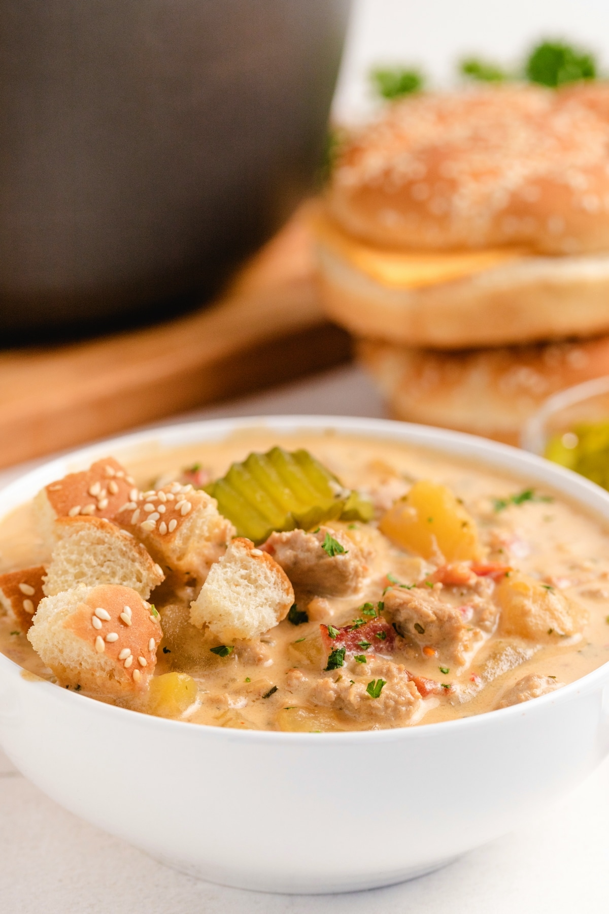 Cheeseburger soup with toasted buns on top