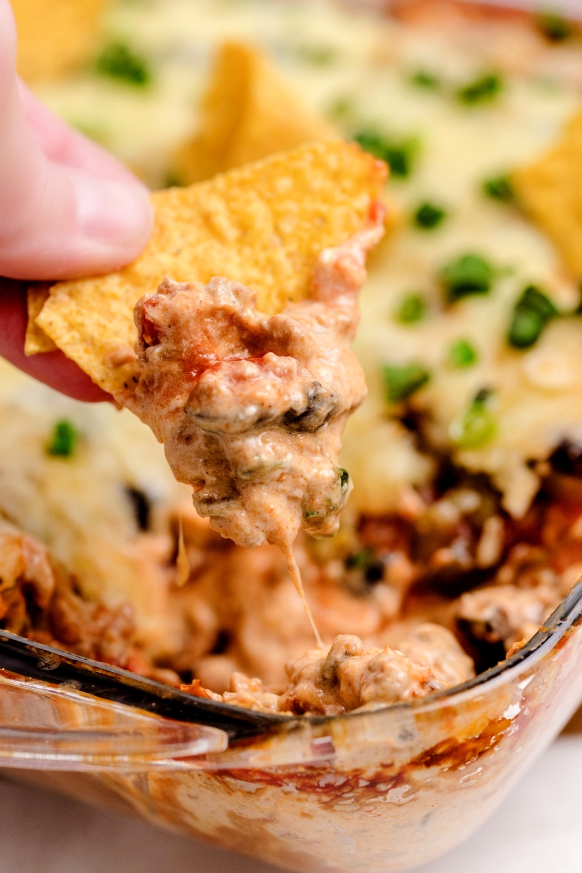 Overhead shot of baked taco dip with melted cheese, olives, and green onions.