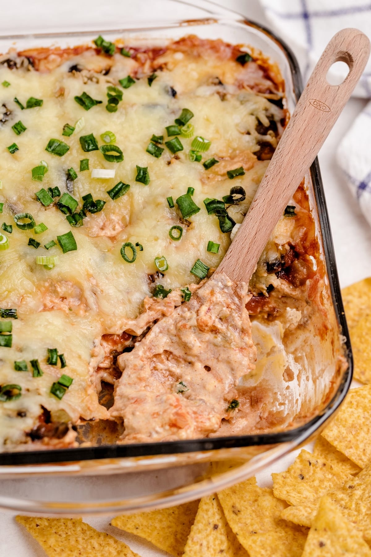 wooden spoon scooping out baked taco dip