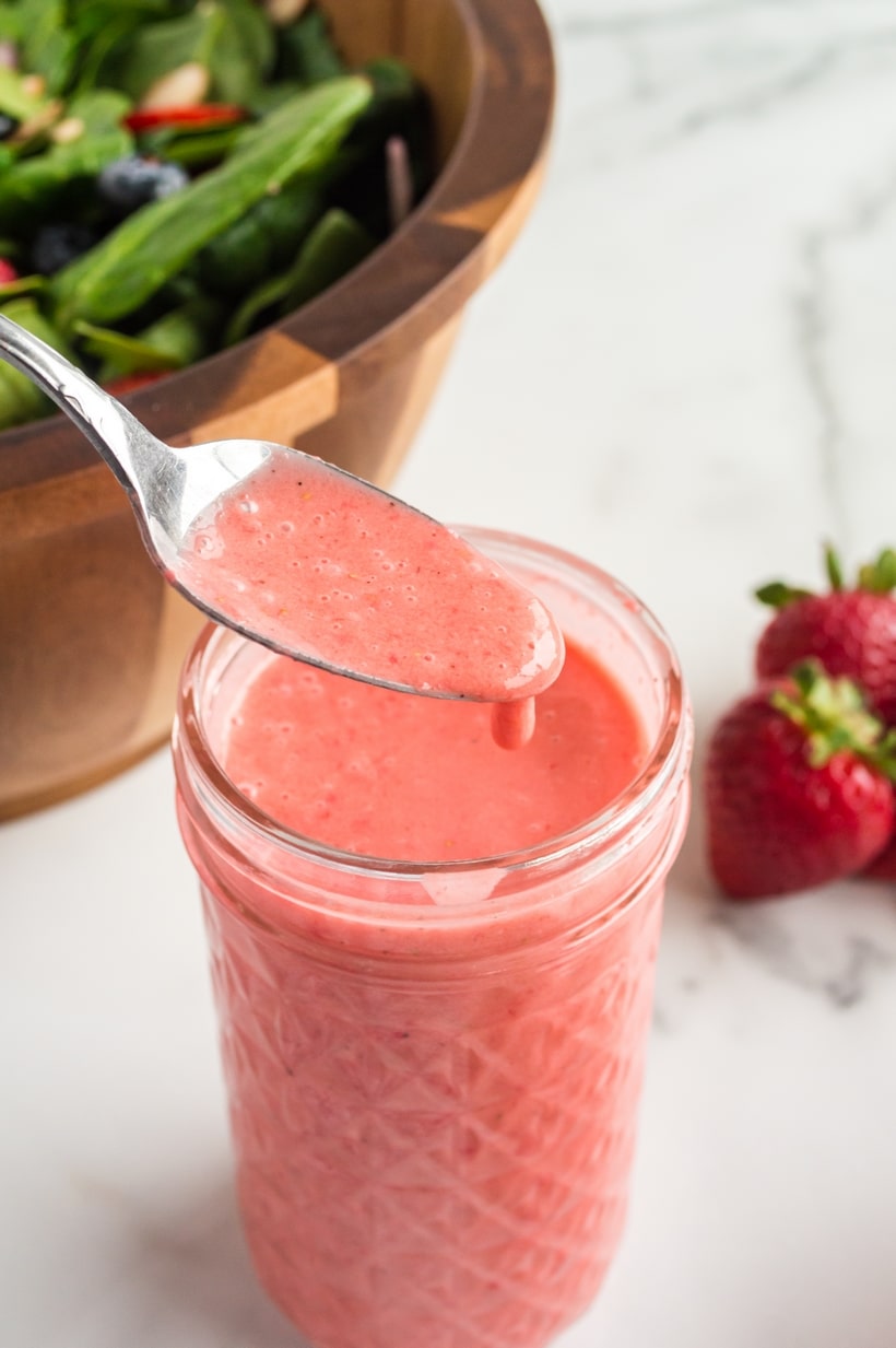Strawberry Spinach Salad with Strawberry Vinaigrette in a mason jar Mason jar filled with homemade strawberry vinaigrette, showing its smooth, vibrant pink color.