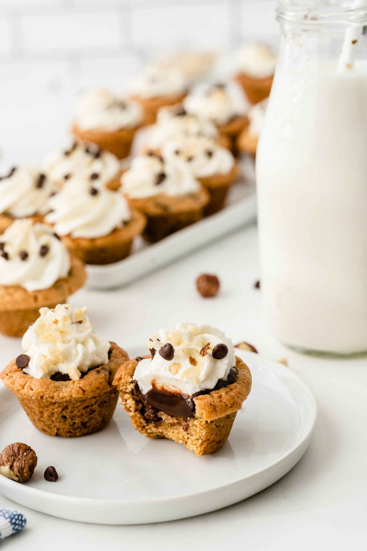 Mini muffin tin cookie cups with a soft cookie shell and Nutella chocolate filling Chocolate chip cookie cups with Nutella filling and whipped cream on a dessert plate
