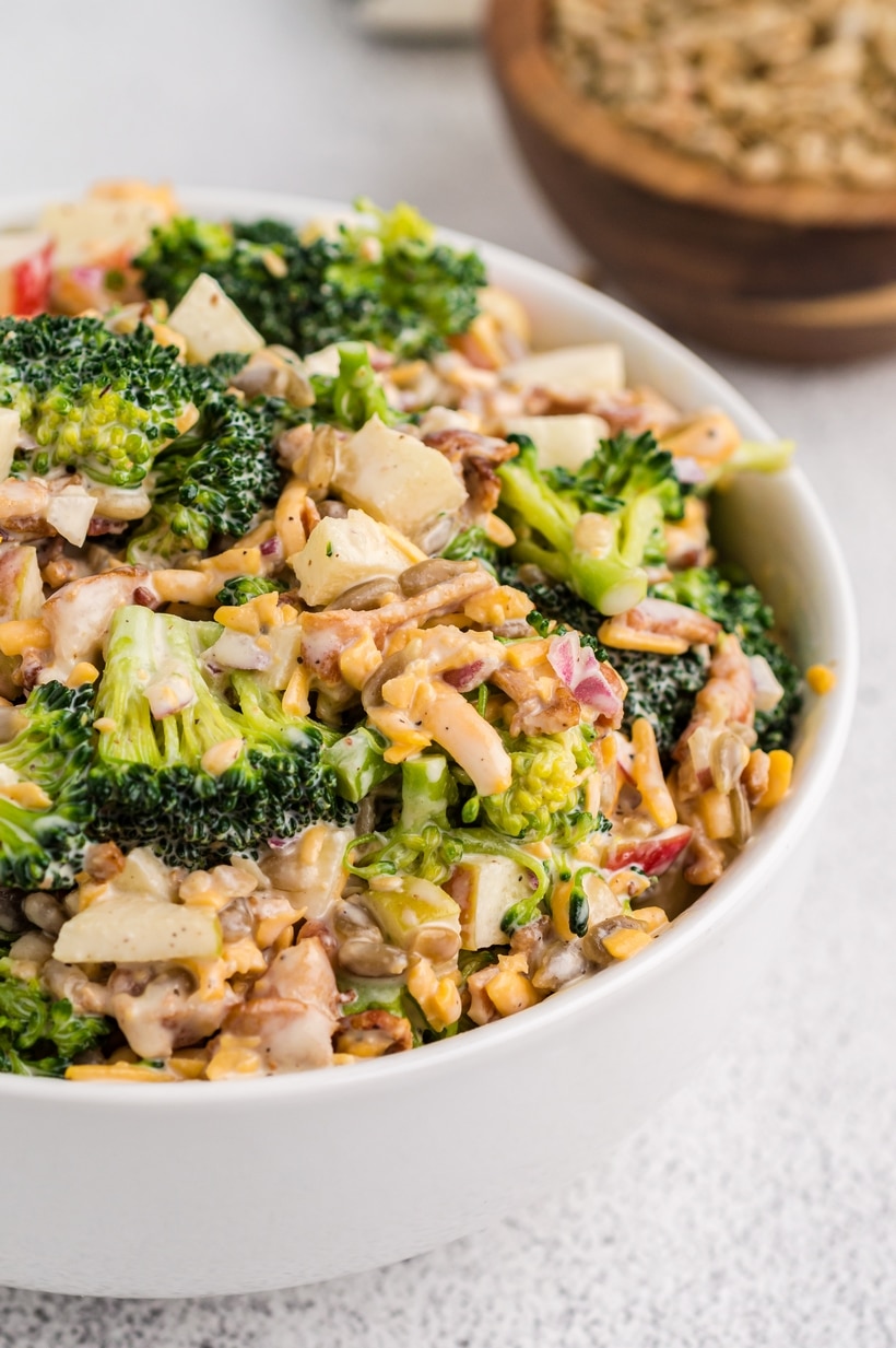 Bacon Broccoli Salad top view A fully prepared bacon broccoli salad in a large serving bowl, showcasing the mix of fresh broccoli, bacon, apple, and sunflower seeds.