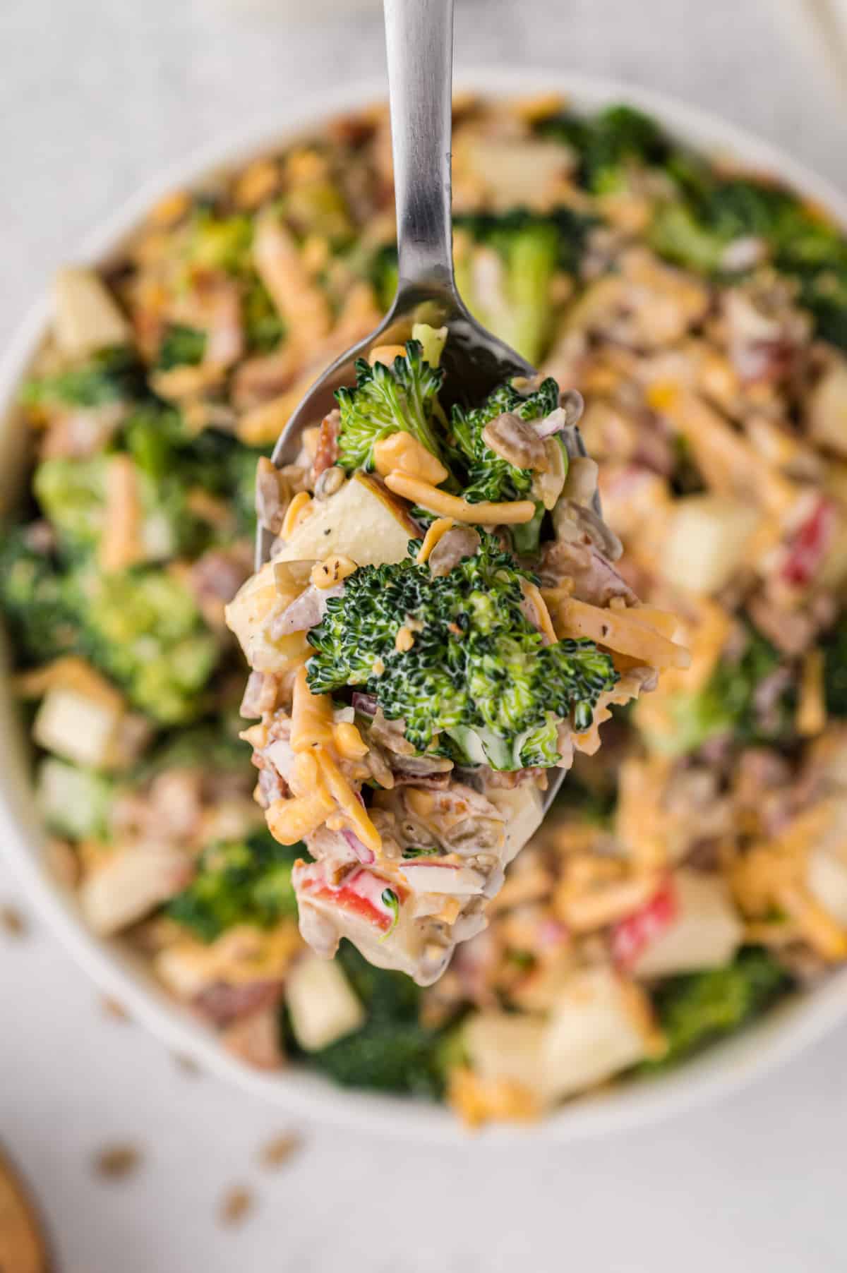 A spoonful of Bacon Broccoli Salad A spoon scooping up a bite of the salad, showing the creamy dressing clinging to the broccoli and other ingredients.