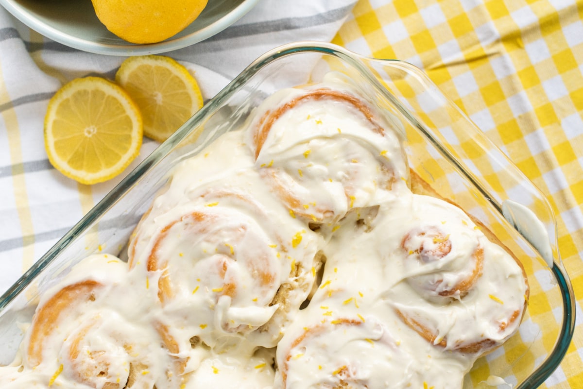 Freshly baked lemon buns in a rectangular baking dish, golden brown and swirled with lemon filling.