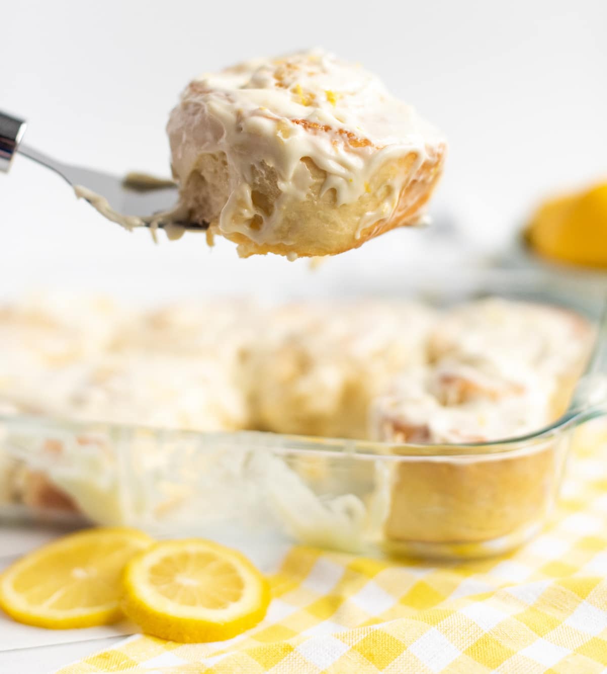 A spatula lifting a lemon bun from the baking dish, showing its soft texture and layers of filling.
