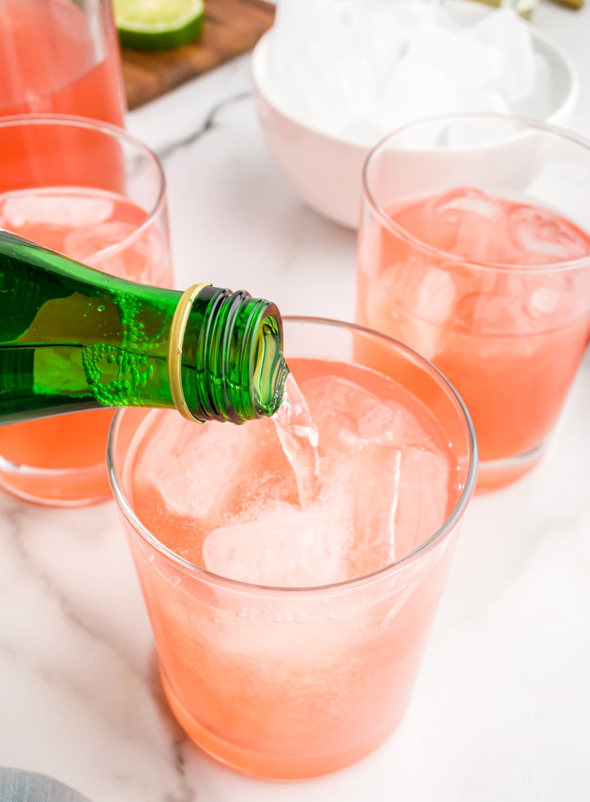 Lime sparkling water being poured into a glass of spicy watermelon margarita