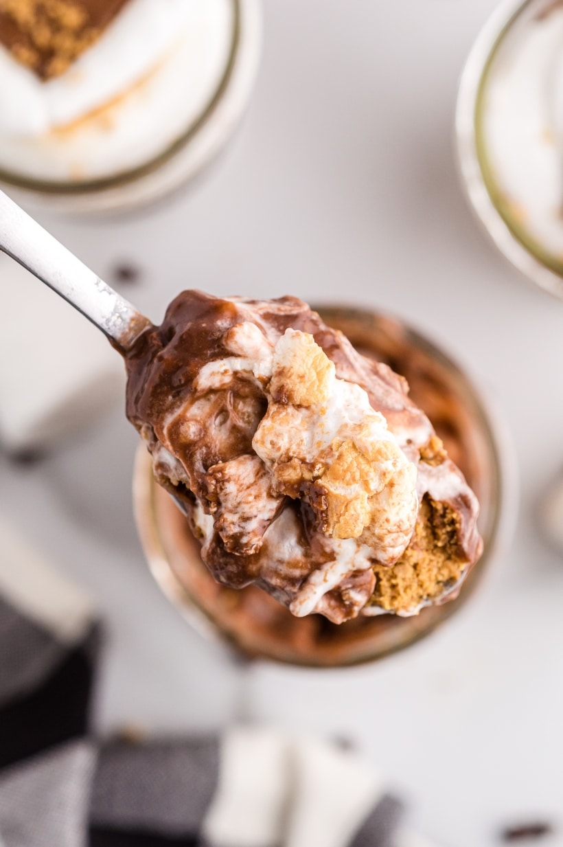 Close-up of spoon with layered s’mores parfait ingredients Spoonful of s’mores pudding parfait showing creamy chocolate, marshmallow, and graham cracker texture