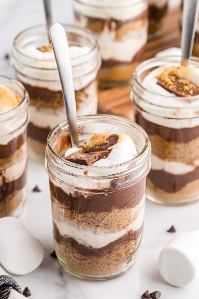 S’mores parfait jar layered with pudding, graham crumbs, and toasted marshmallow Close-up of a no-bake s’mores parfait in a jar with visible layers of graham cracker, chocolate pudding, and marshmallow topping