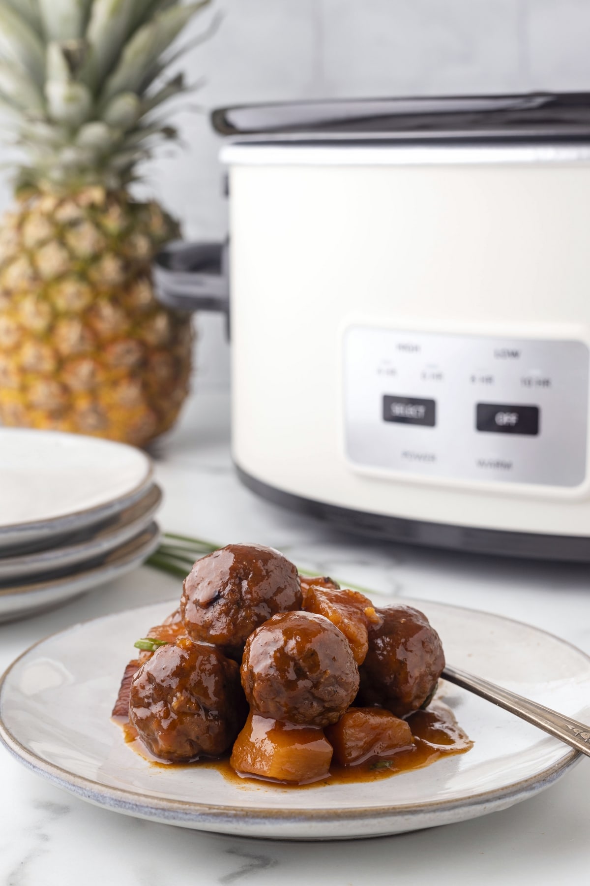Garnished Hawaiian meatballs ready to impress at your next gathering. Plated Slow Cooker Hawaiian Meatballs with pineapple chunks and sauce, perfect for a party appetizer.