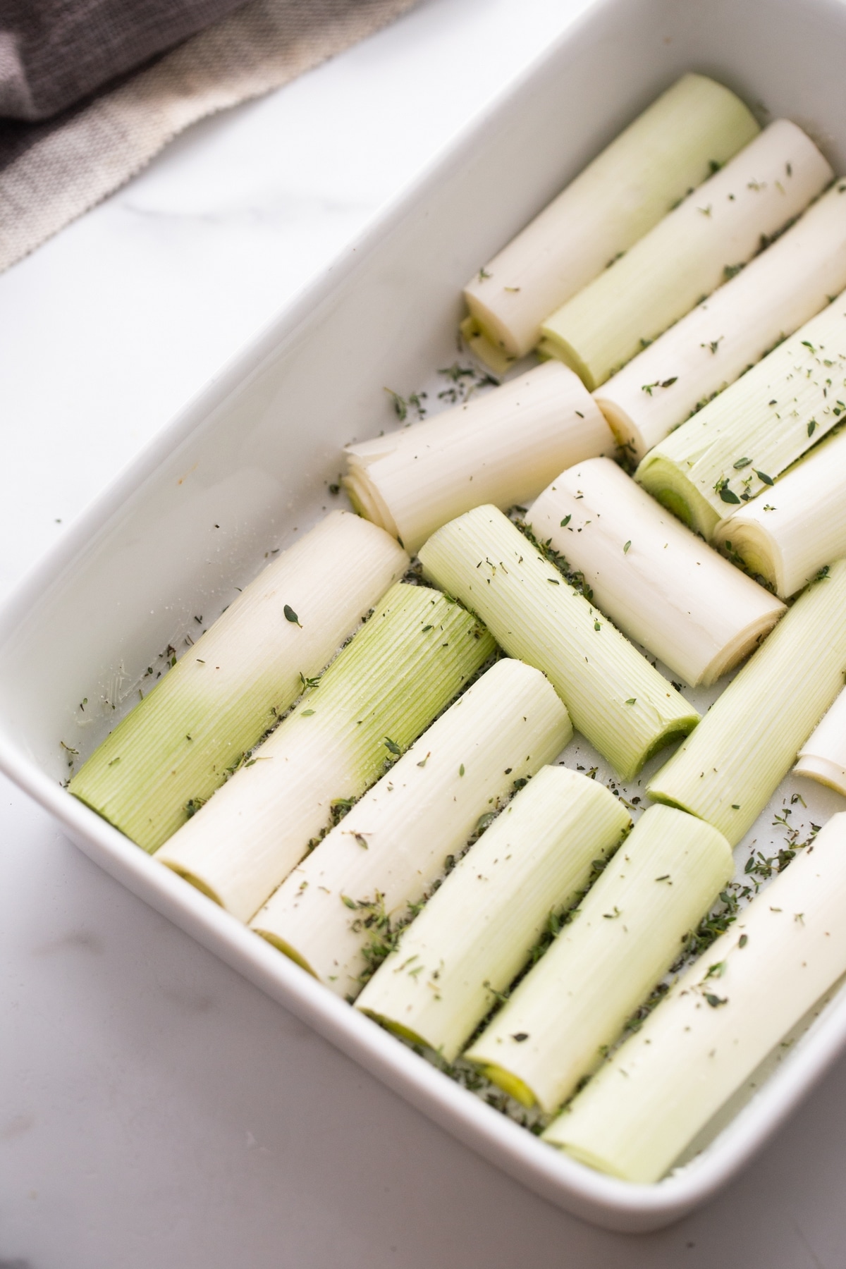 Creamy Roasted Leeks ready to bake. raw leeks sprinkled with fresh thyme