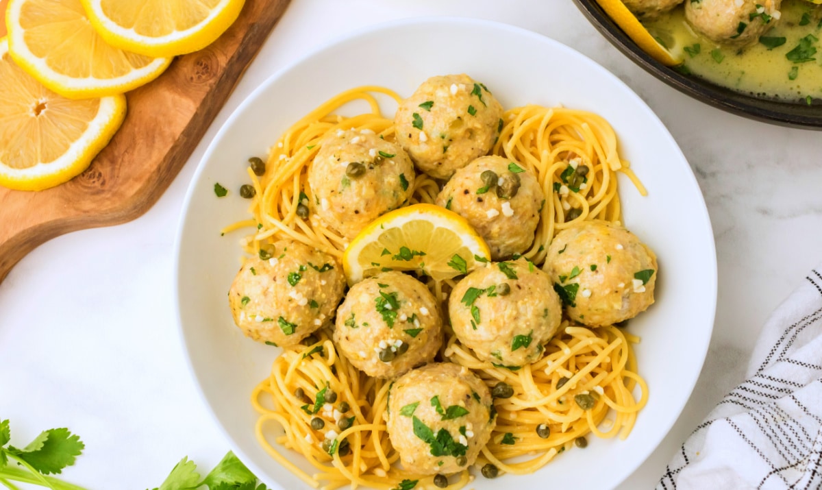 plated chicken piccata meatballs with lemon-caper sauce Overhead shot of chicken piccata meatballs plated with pasta and caper sauce