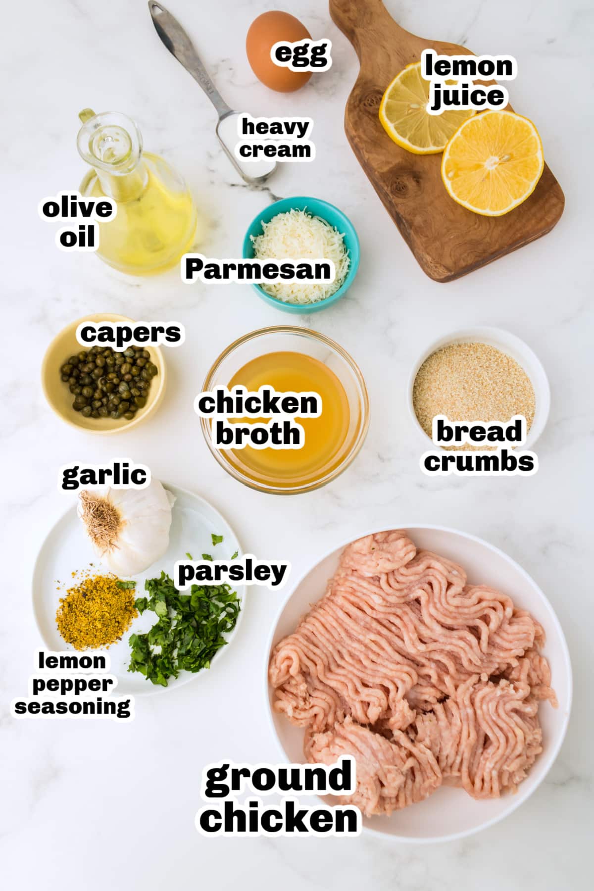ingredients for baked chicken piccata meatballs Ingredients for chicken piccata meatballs arranged on a surface with lemon, capers, and ground chicken