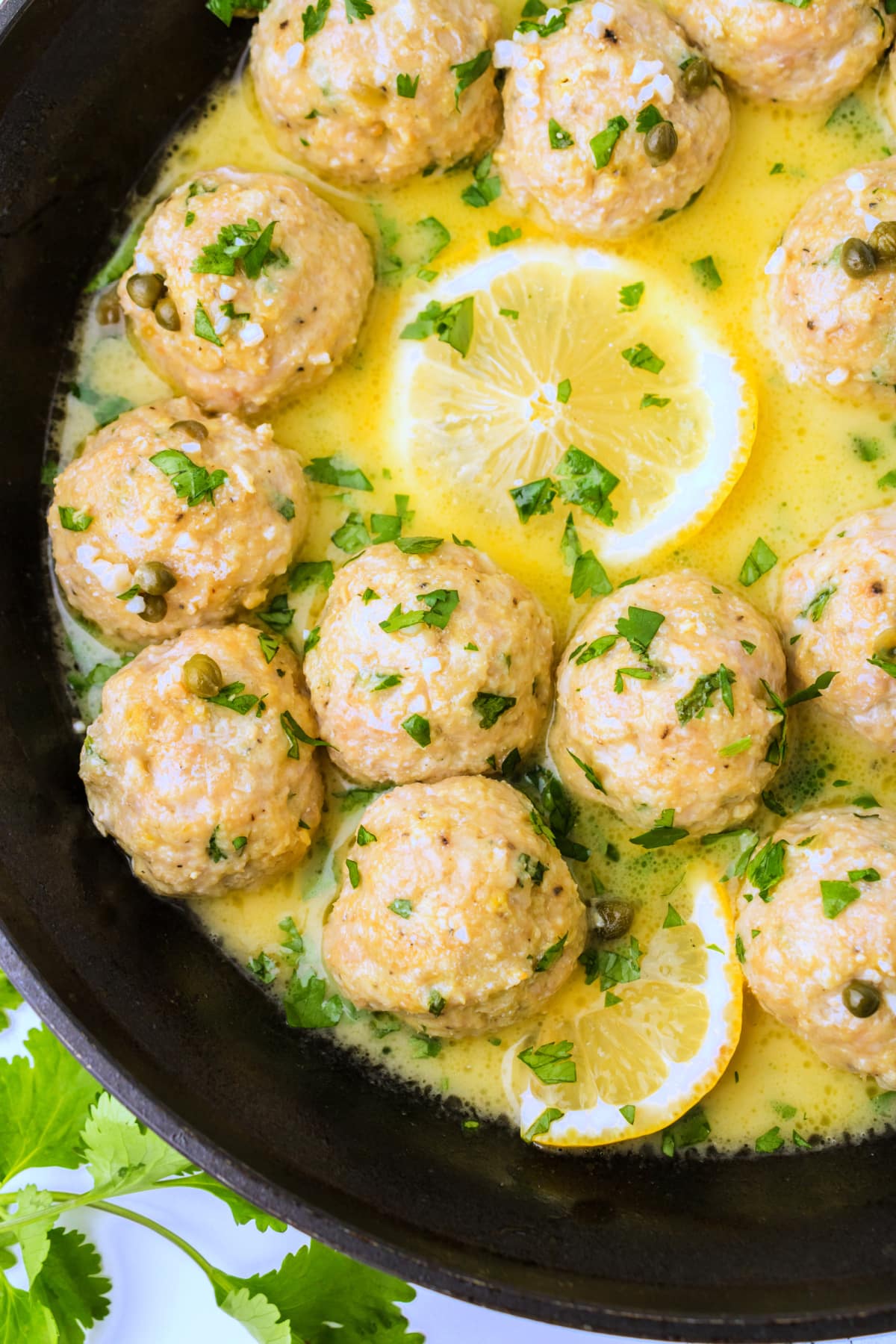 chicken piccata meatballs in skillet with lemon butter sauce Closeup overhead shot of chicken piccata meatballs in skillet coated in lemon butter sauce