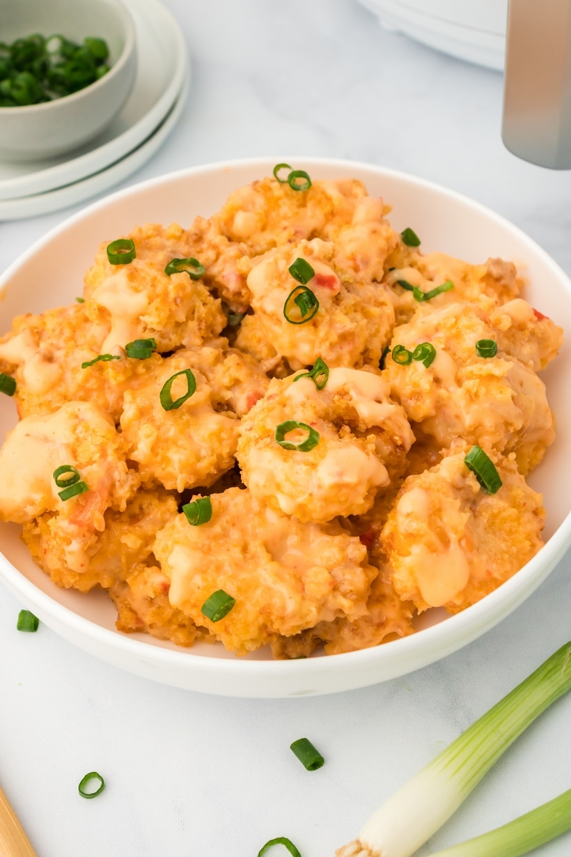 air fryer bang bang shrimp recipe finished and plated Bowl of air fried shrimp coated in bang bang sauce, ready to serve