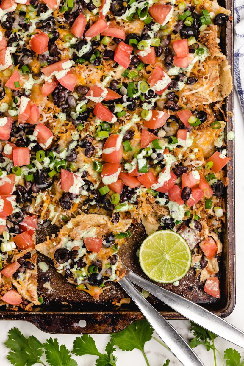 It's time to add these sheet pan chicken nachos with a creamy lime drizzle to your weekly meal plan. These loaded nachos are quick, flavorful, easily customizable and budget friendly. I make them whenever I find myself with leftover rotisserie chicken. sheet pan chicken nachos with creamy lime drizzle