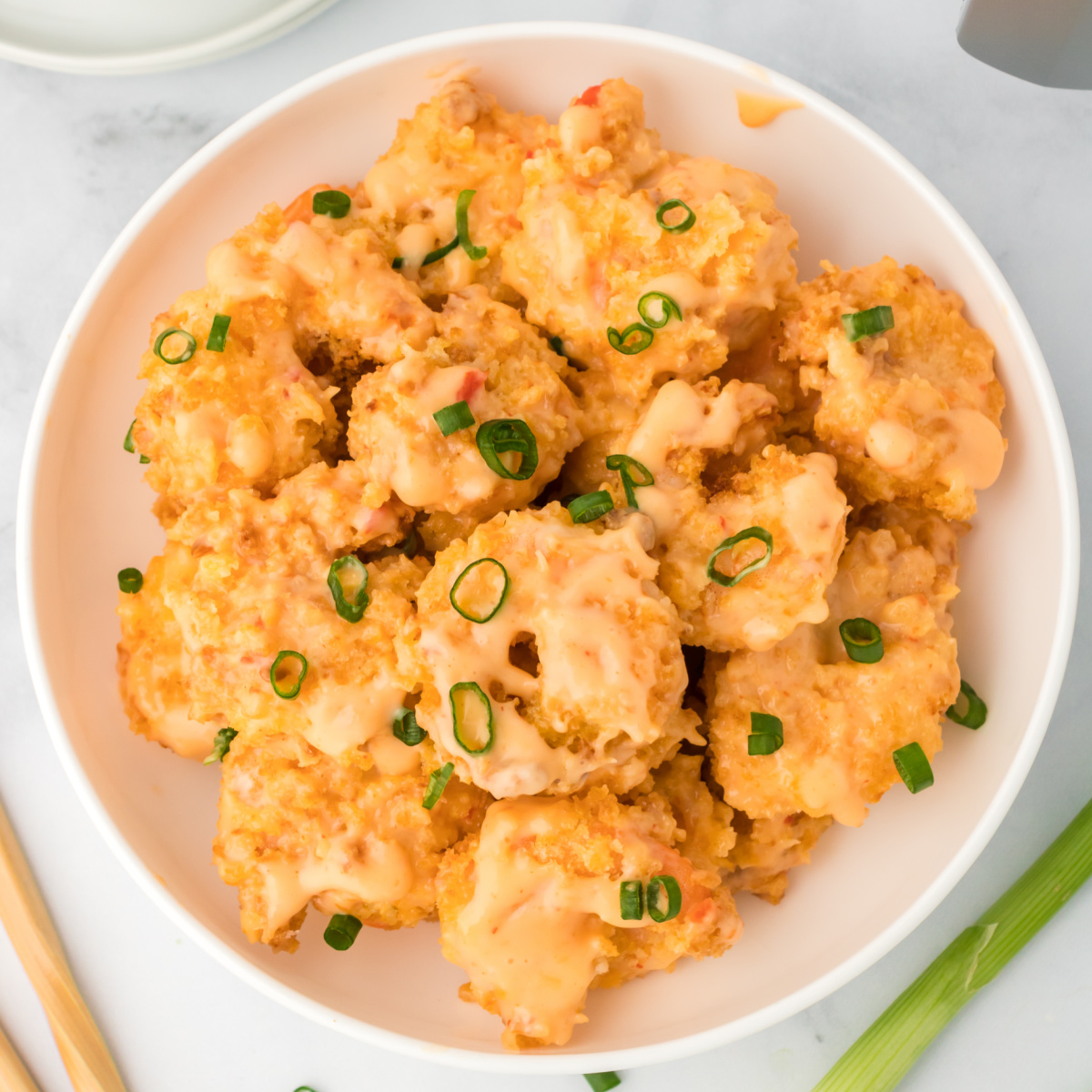 golden air fryer shrimp coated in sweet chili and Sriracha Close overhead view of crispy air fried shrimp tossed in bang bang sauce