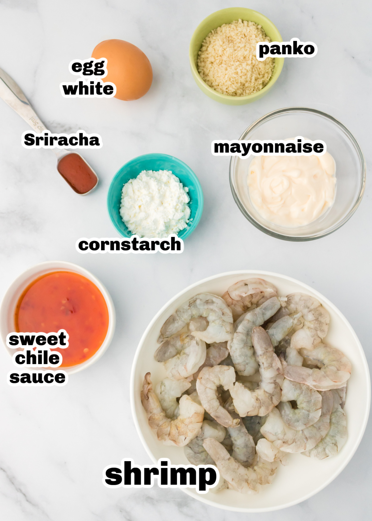 raw shrimp, panko, cornstarch, egg white, mayo, sweet chili sauce, Sriracha Ingredients for air fryer bang bang shrimp laid out on a white surface