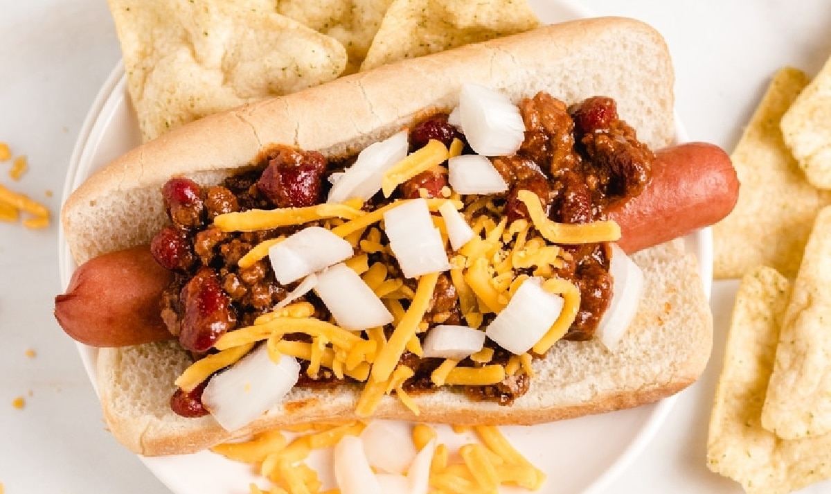 Overhead view of one fully topped chili dog on a bun