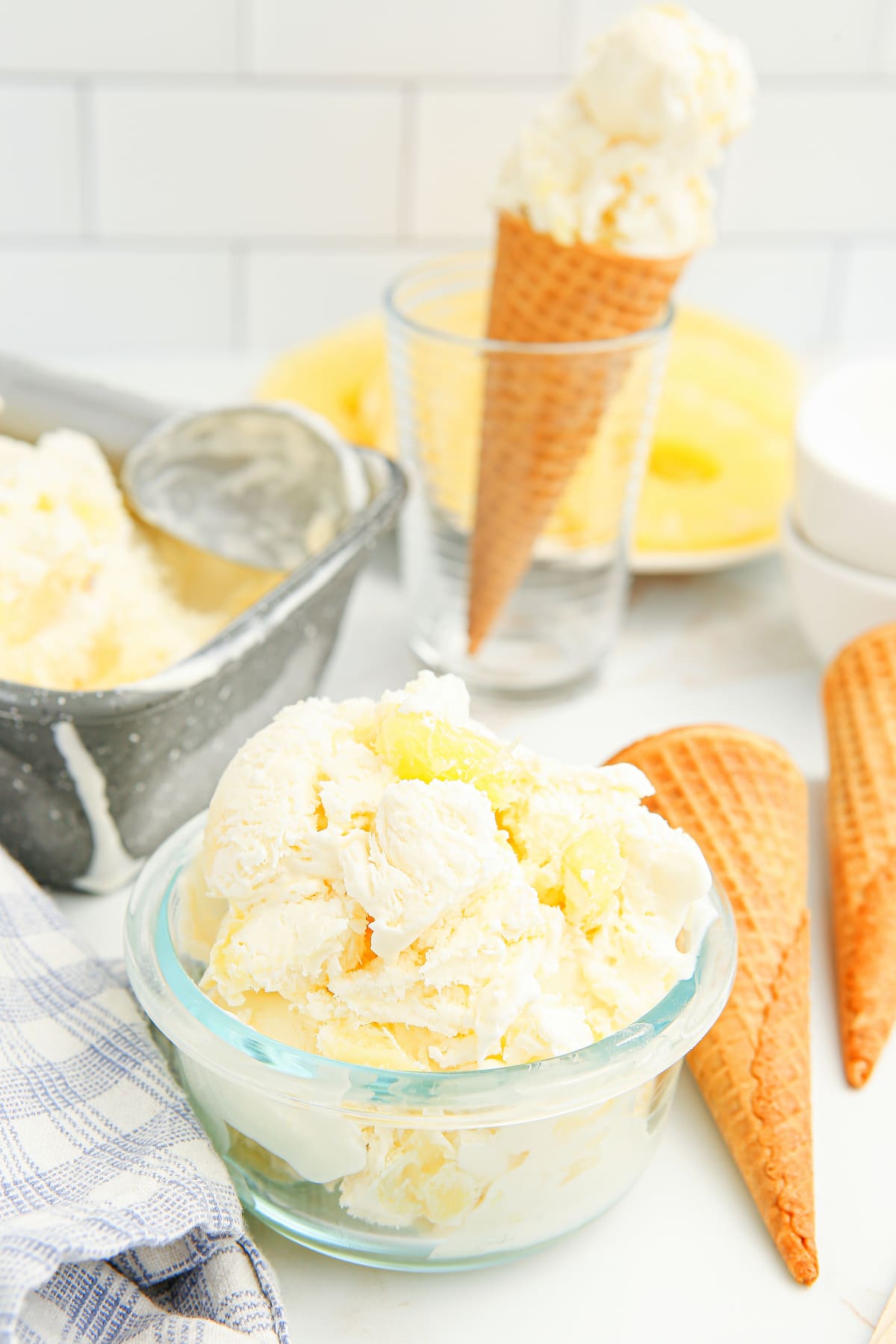 Bowl of no-churn pineapple ice cream with sugar cones in the background
