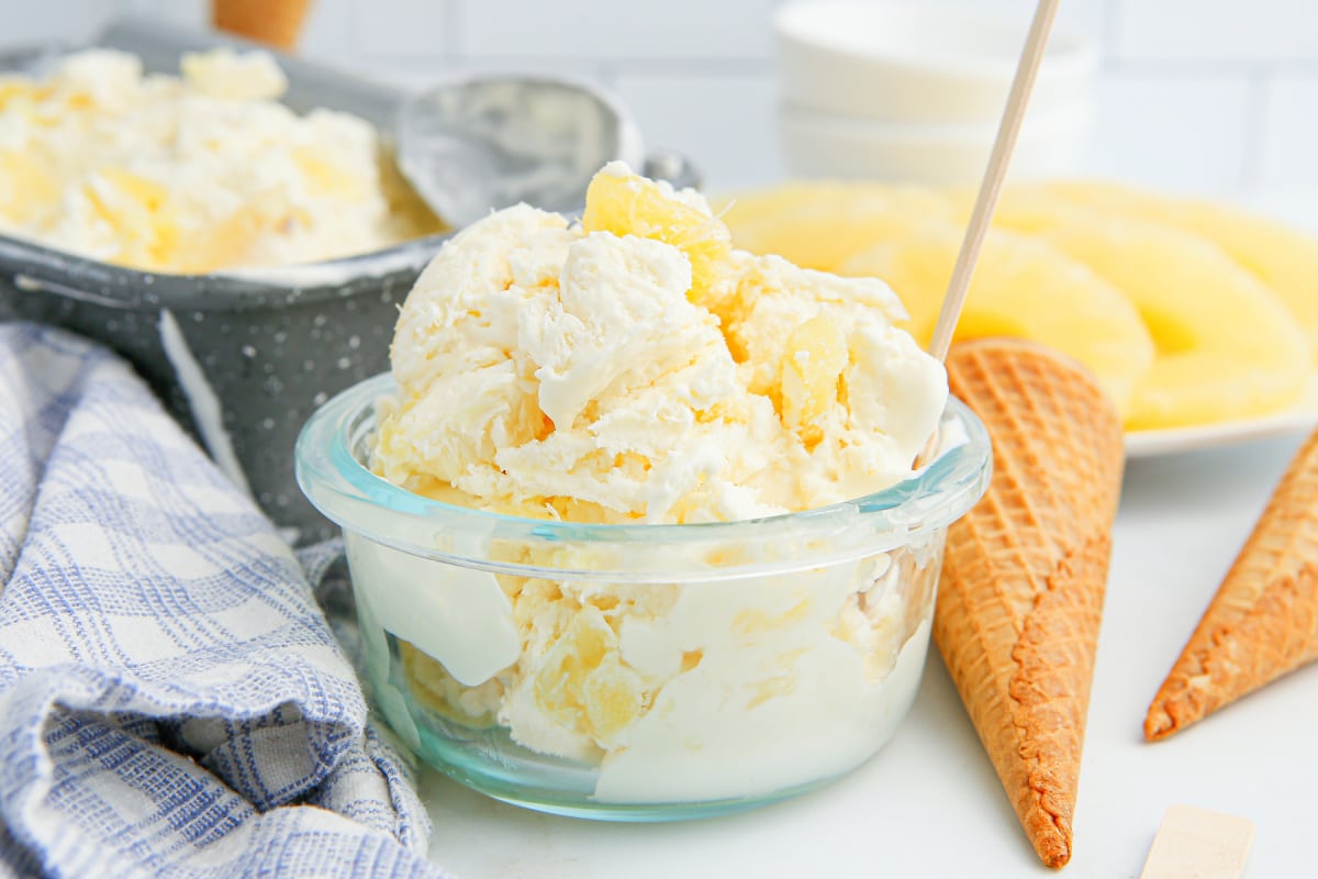 Creamy no-churn pineapple ice cream packed into a clear glass bowl