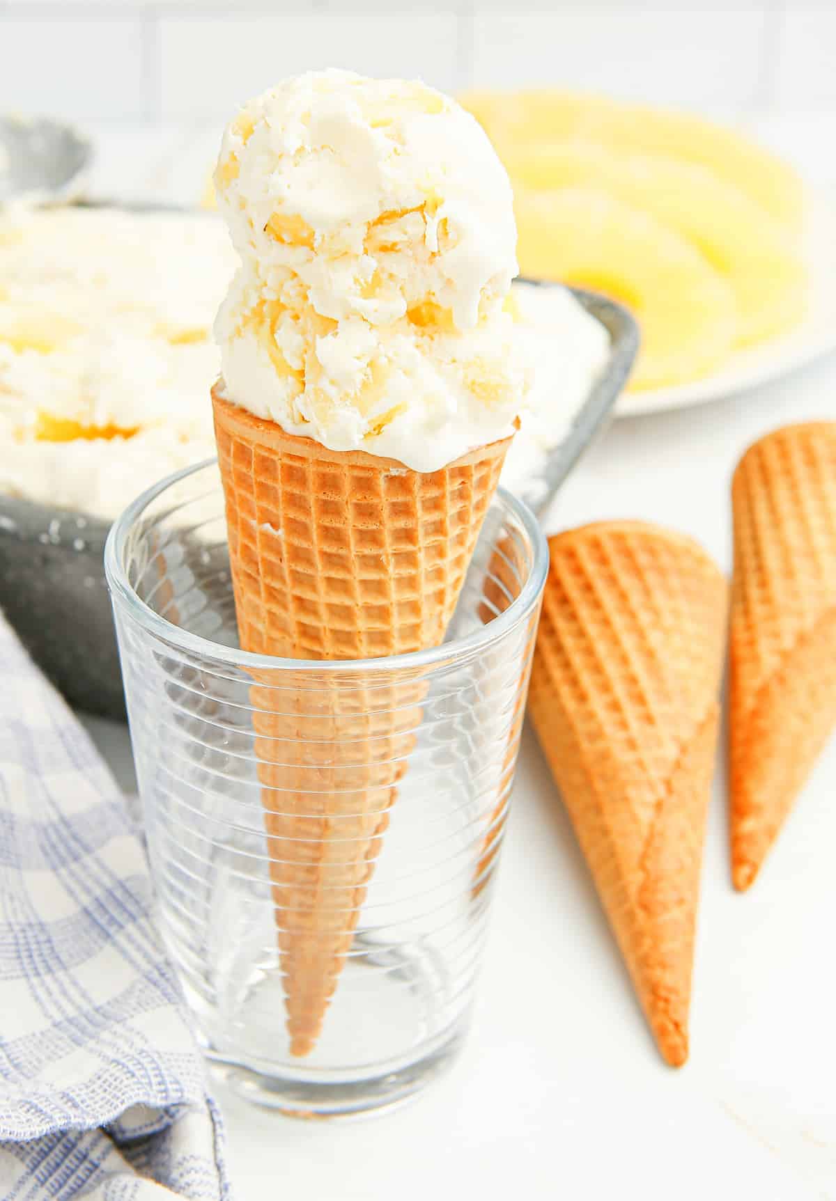 Ice cream cone with two scoops of pineapple ice cream standing in a glass