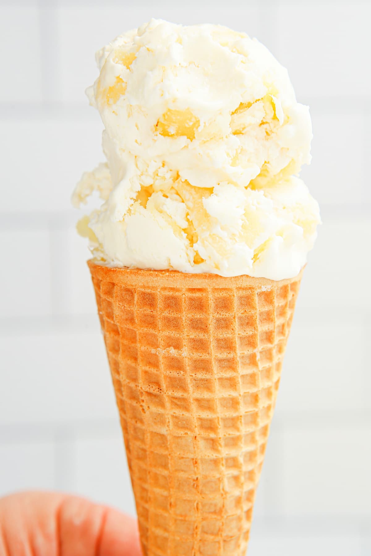 Scoop of no-churn pineapple ice cream in a sugar cone
