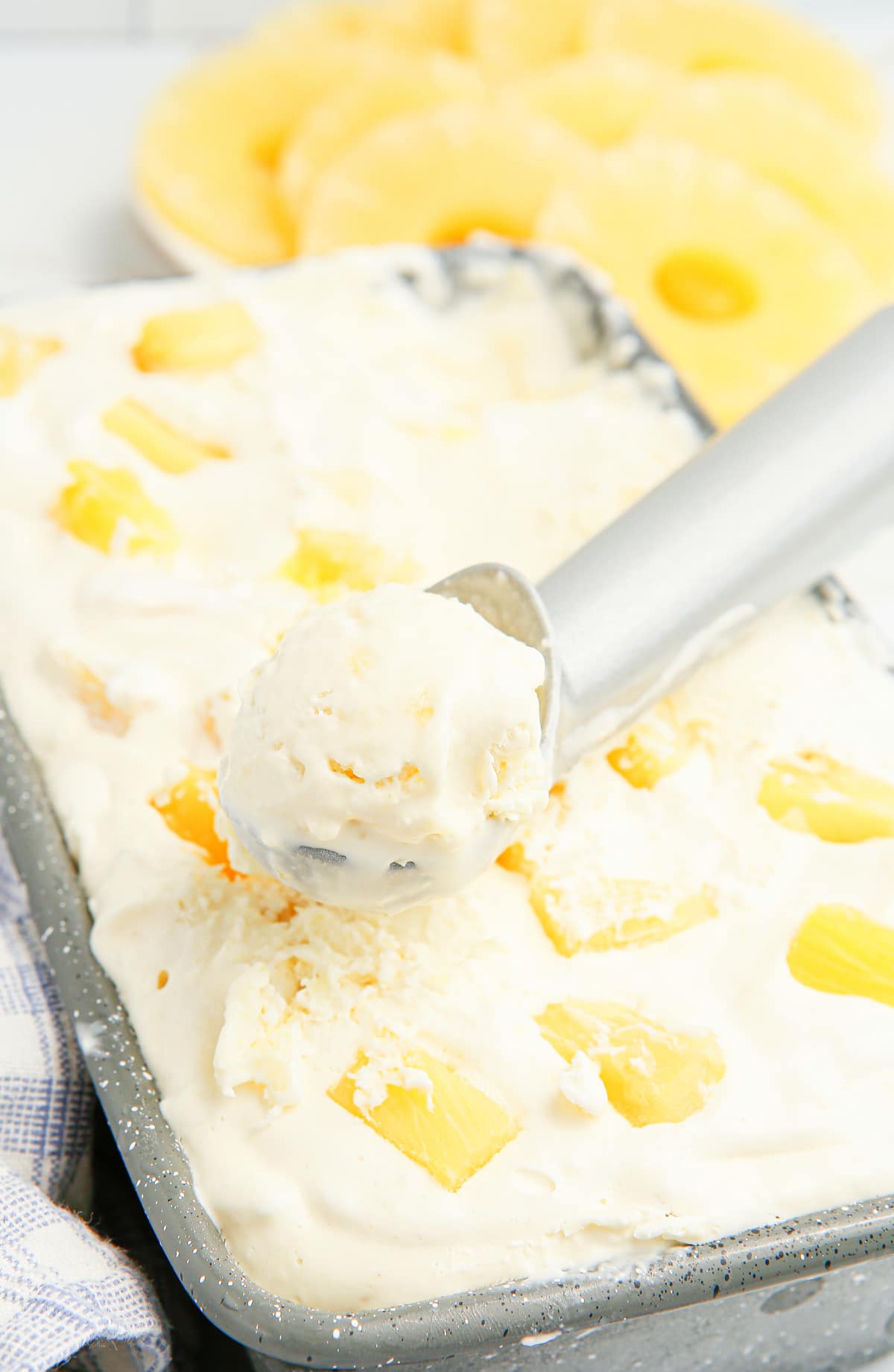 No-churn pineapple ice cream being scooped from a loaf pan