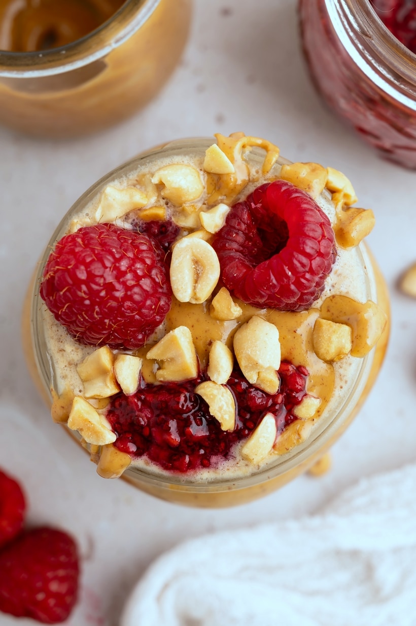 Peanut Butter and Jelly Overnight Oats with a drizzle of peanut butter and fresh raspberries.