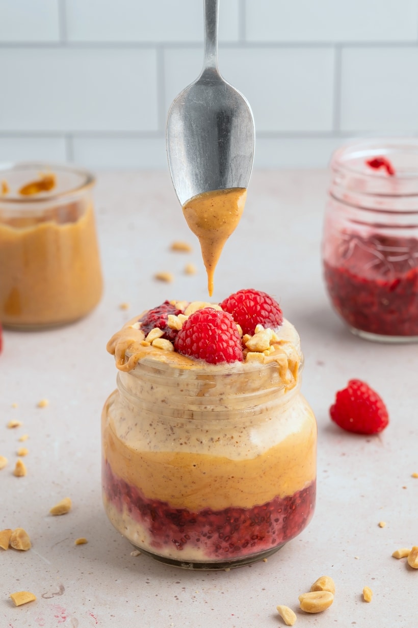 Spoon scooping out Peanut Butter and Jelly Overnight Oats from a jar.