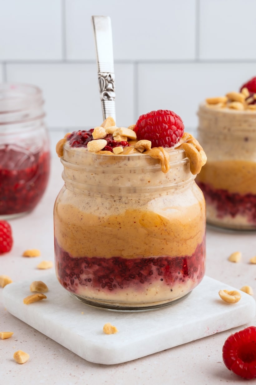 Jar of Peanut Butter and Jelly Overnight Oats topped with peanut butter and raspberry jam