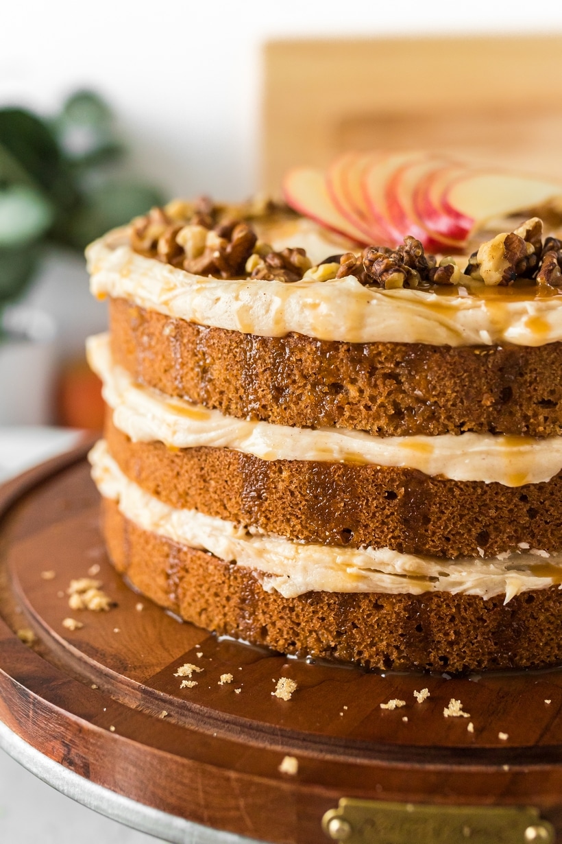 Layered Caramel Apple Cake on Wooden Stand Side view of a multi-layered caramel apple cake on a rustic wooden cake stand